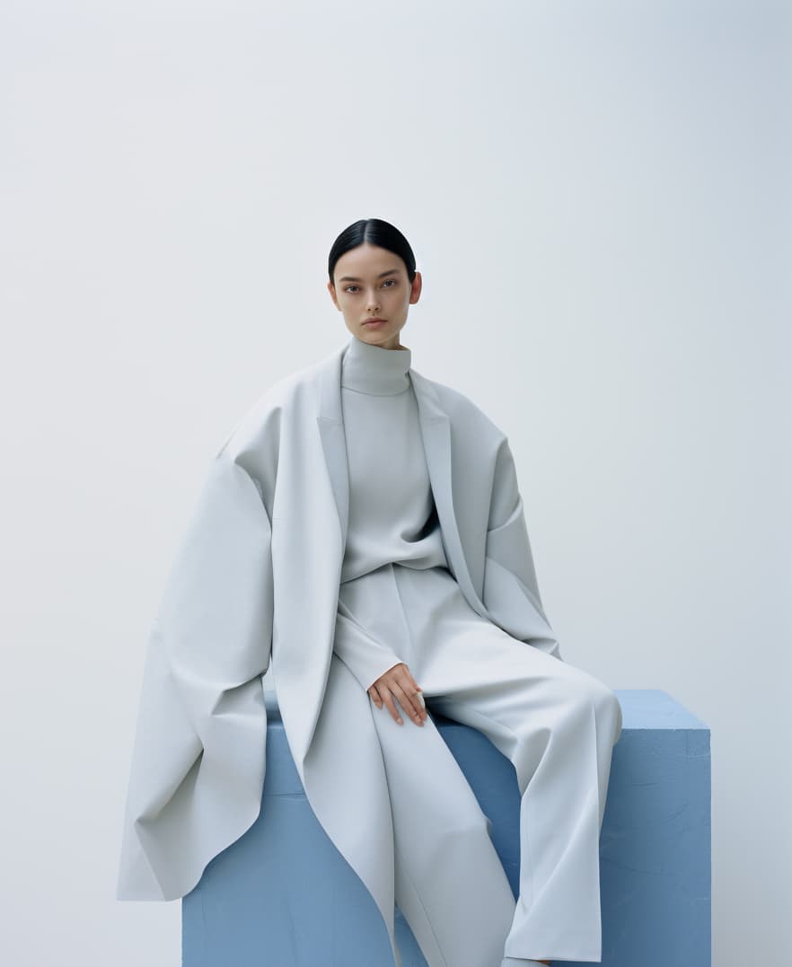 AI generated: a woman sitting on top of a white cube, official jil sander editorial, blue and grey tones, trending...