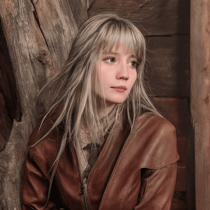 AI generated: Raw face Shini, looking forward, sitting in old wood house, hair rippling in the wind, european woma...