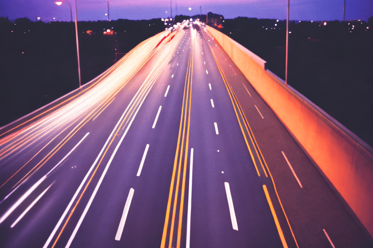 AI generated: 35mm film photograph from an overpass, blurry motion lights, blue hour, grainy, cinematic