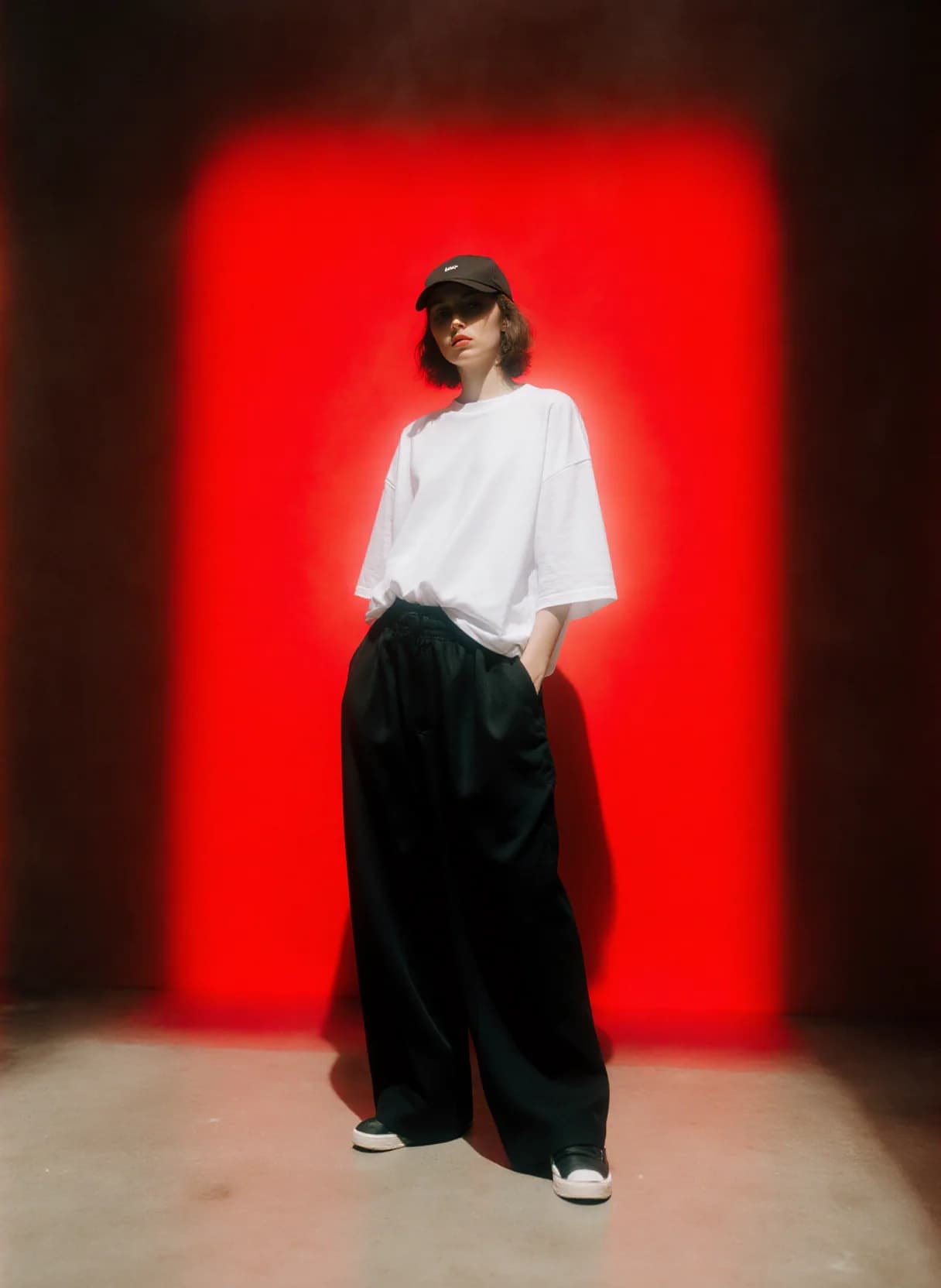 AI generated: A person stands confidently against a stark, dark background illuminated by a bold, intense red ligh...