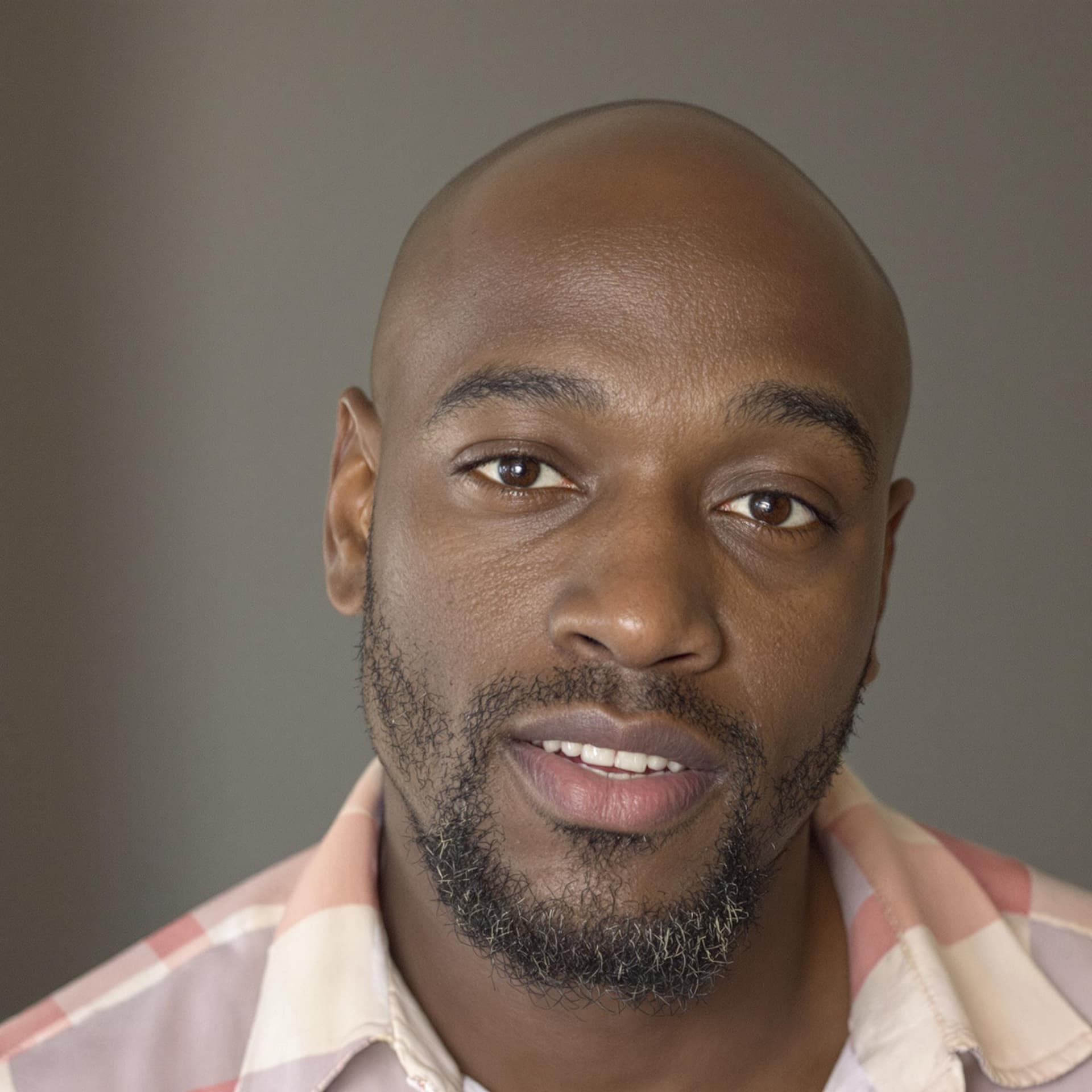 AI generated: a bald black male in his thirties with facial stubble, posing for the camera
