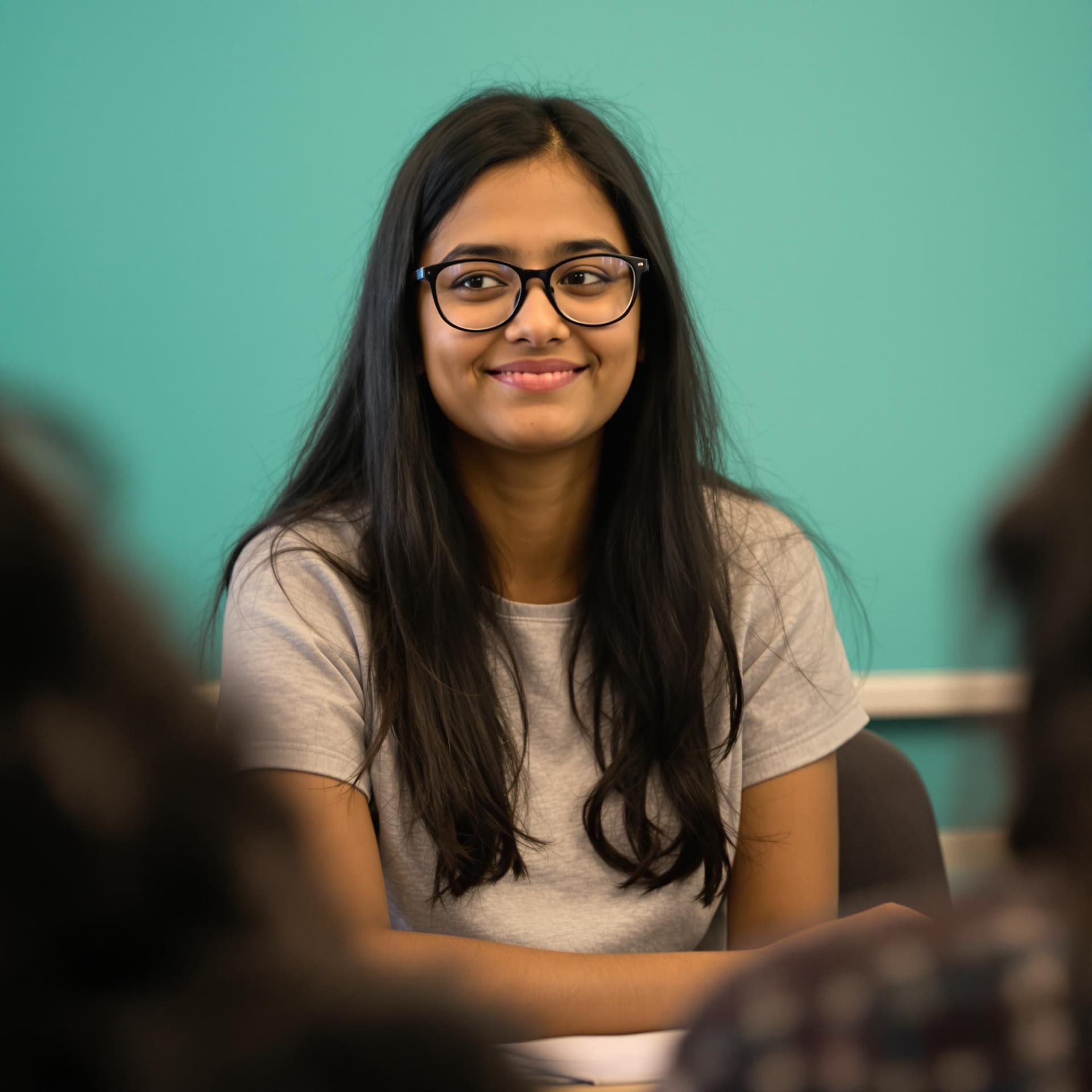 AI generated: The image features a young Indian woman with long, dark hair and glasses, sitting in a relaxed pose....