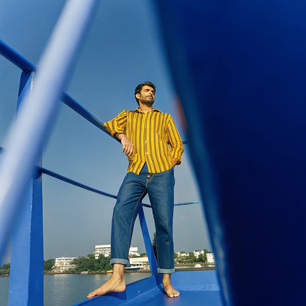 AI generated: create a image for this "A man standing on a boat deck, looking at the camera." in a striped shirt a...