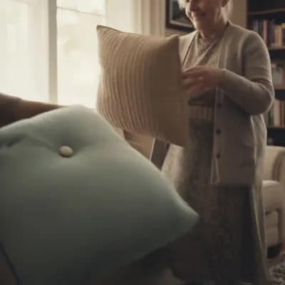 AI generated video: An extreme close-up shot of an elderly woman's wrinkled, gentle hand lifting a plush, velvet cushion...