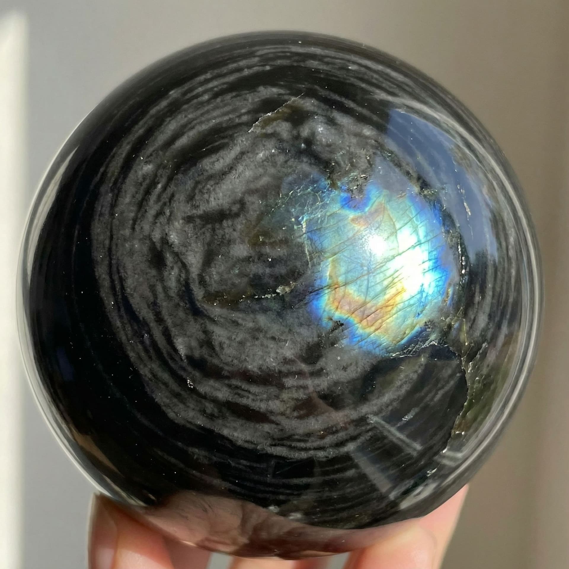 AI generated: Black obsidian with grey whips flowing through it like clouds and it has a shine like labradorite 
