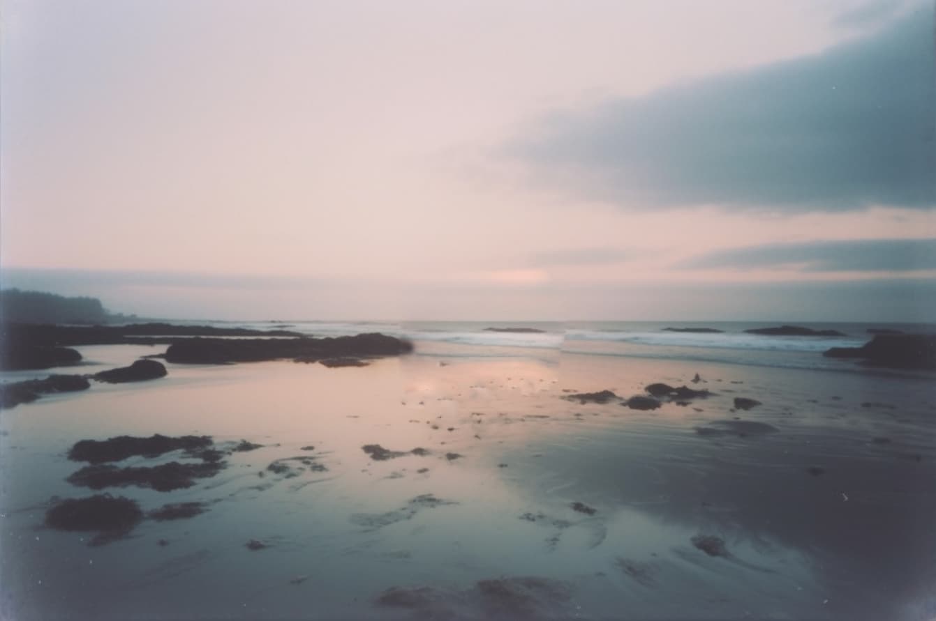 AI generated: a polaroid picture of a body of water, soft-sanded coastlines, pastel sky, ocean shoreline on the ho...