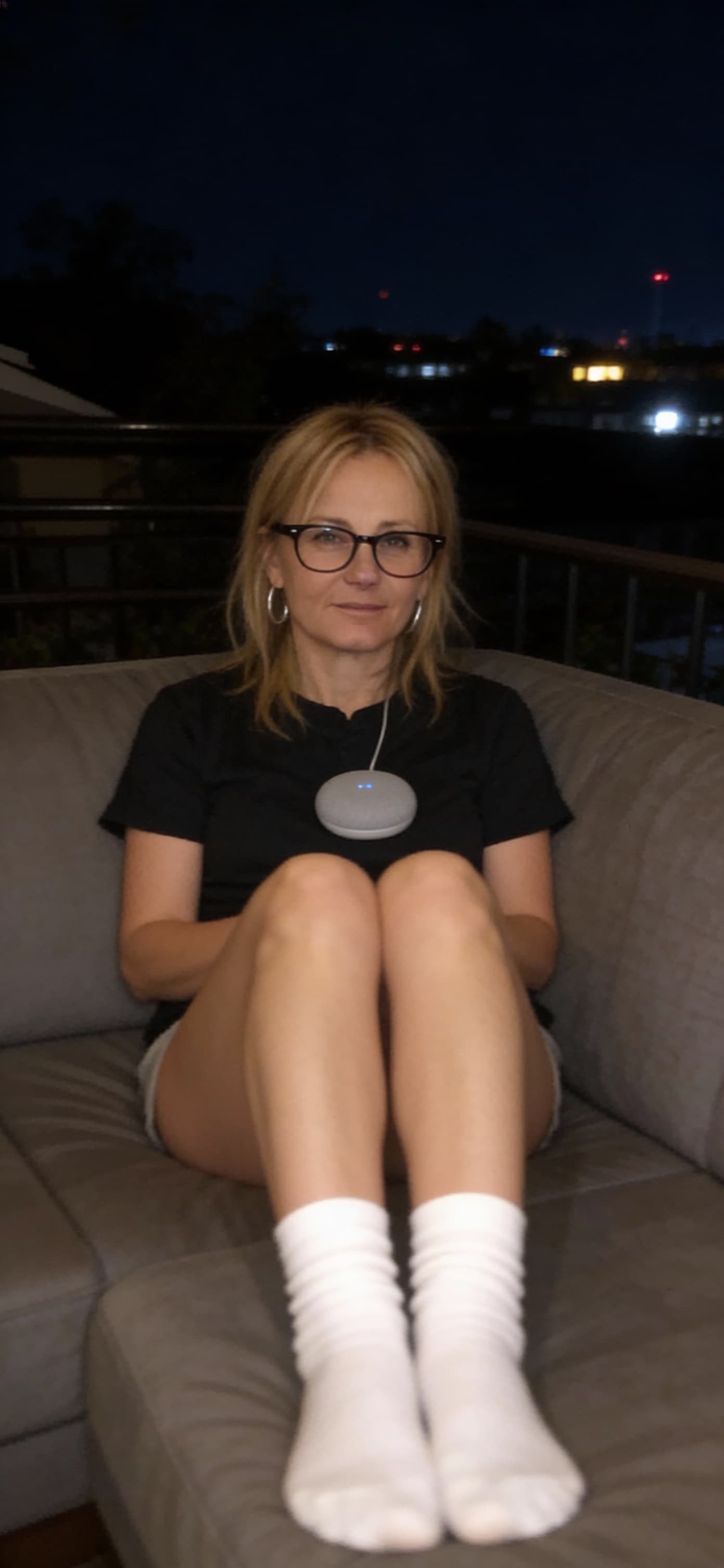 AI generated: looking at me,a sloppy snapshot. Sitting on a couch at night, home mini top and white socks, glasses...