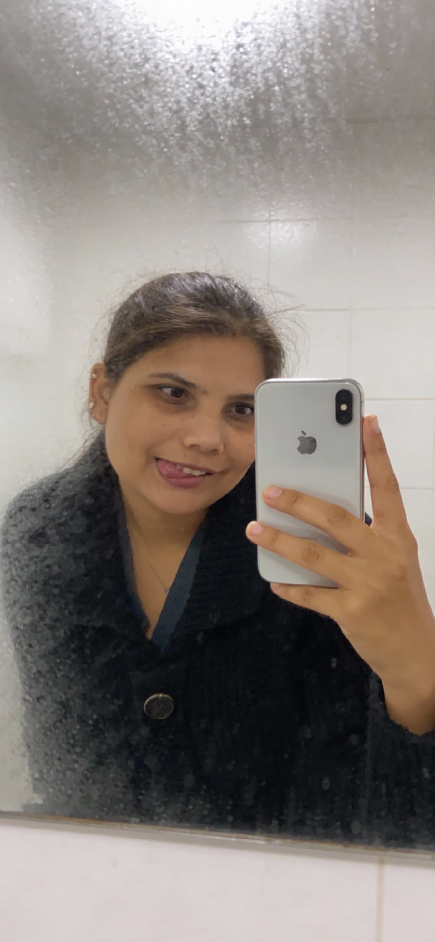 AI generated: Casual mirror selfie in a bathroom, smartphone photo quality. adult with a playful expression, bitin...
