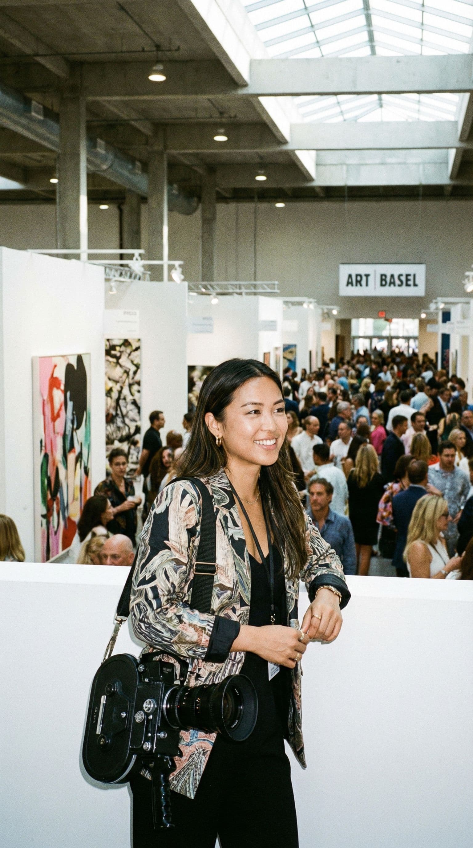 AI generated: A person standing in front of a vertical aspect ratio camera at art basel with a crowd behind them