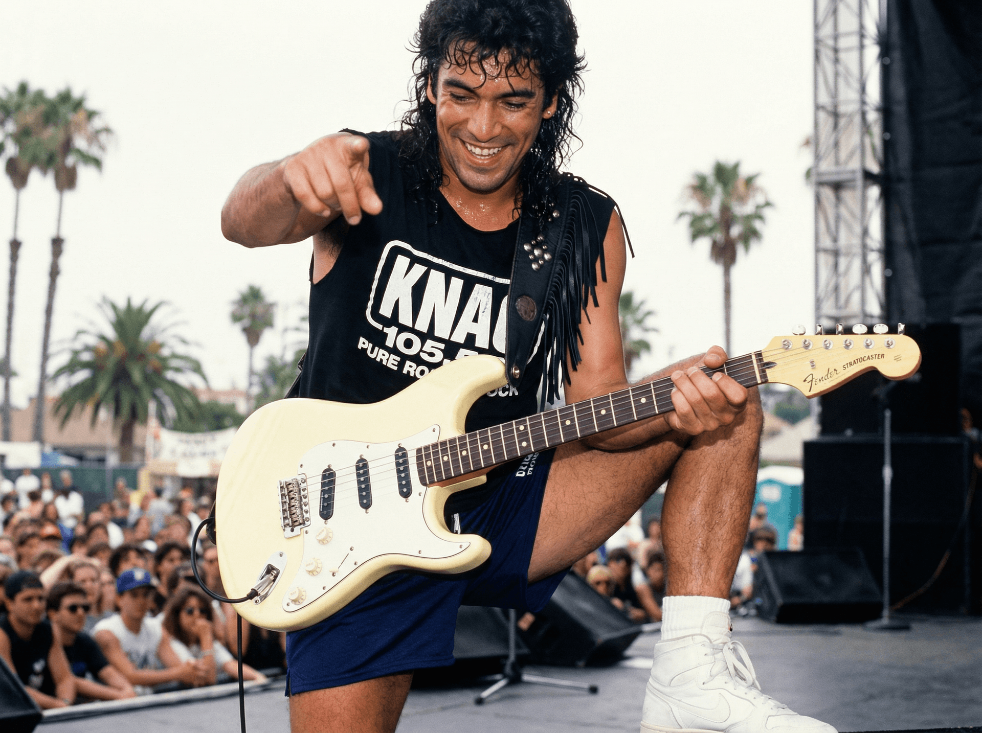 AI generated: Guitar player looks down at the crowd and smiles and points at the camera as he plays on an outdoor ...