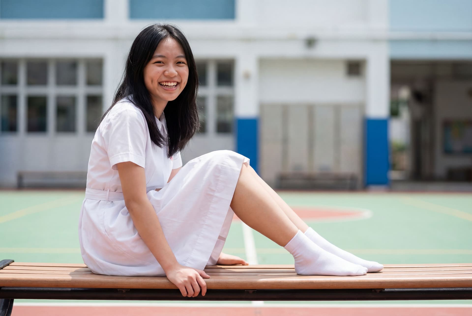 AI generated: 19歲香港女生,穿著全白色夏季中學校服裙,文靜可愛甜美臉孔.大眼睛.有酒窩.黑髮.側拍全身照.自然細緻皮膚.不要過度柔化皮膚.坐在操場椅子.大腿偏瘦.望鏡頭大笑.真實照片.8K UHD.到ankle短...