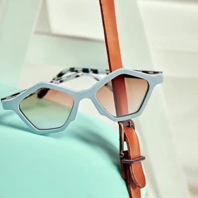 AI generated video: Close-up product shot of stylish geometric sunglasses resting on a pastel turquoise cooler. A soft n...