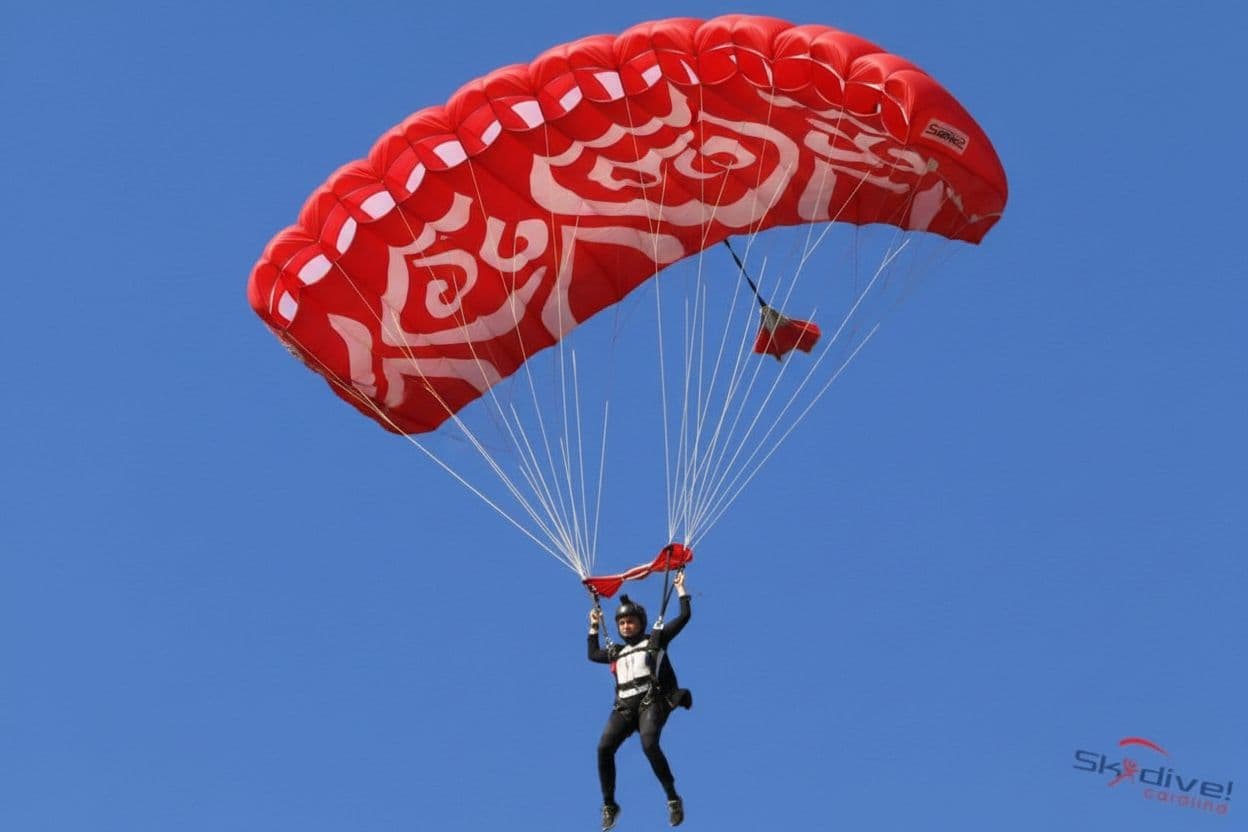AI generated: woman descending from a blue sky with b  in a very huge red and white pattern parachute  realistic 