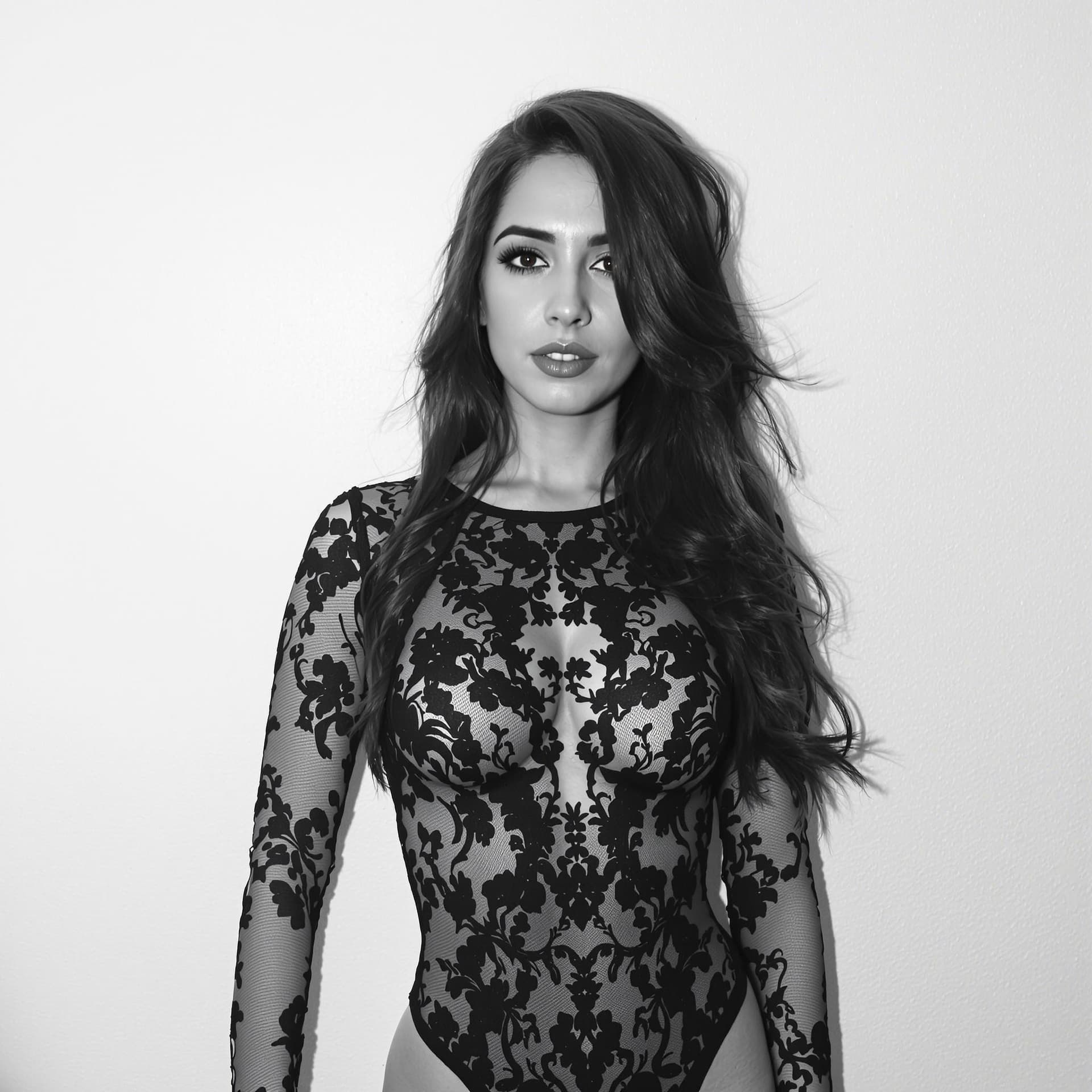 AI generated: Captured in a black and white shot, a woman with long dark hair is wearing a black lace bodysuit. Th...