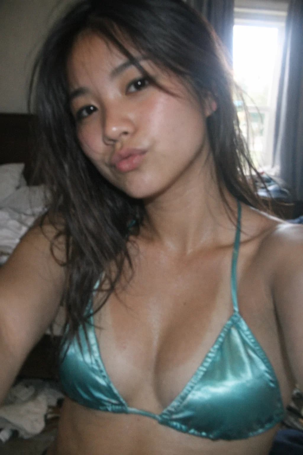 AI generated: (SORA)
a relatively dark selfie of an asian woman with tan lines in satin  swimwear top . Make the l...