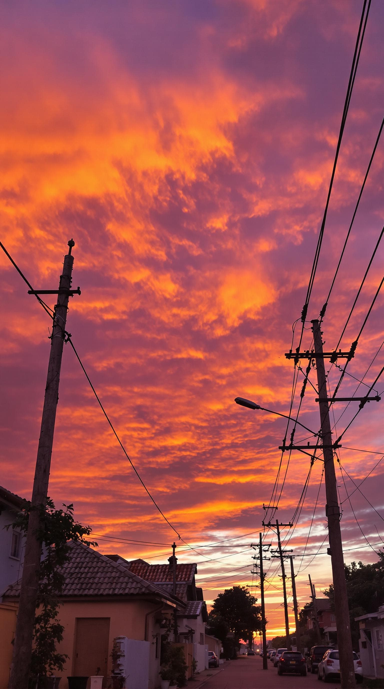 AI generated: A scenic suburban street at sunset is portrayed, with vibrant orange and purple clouds illuminating ...