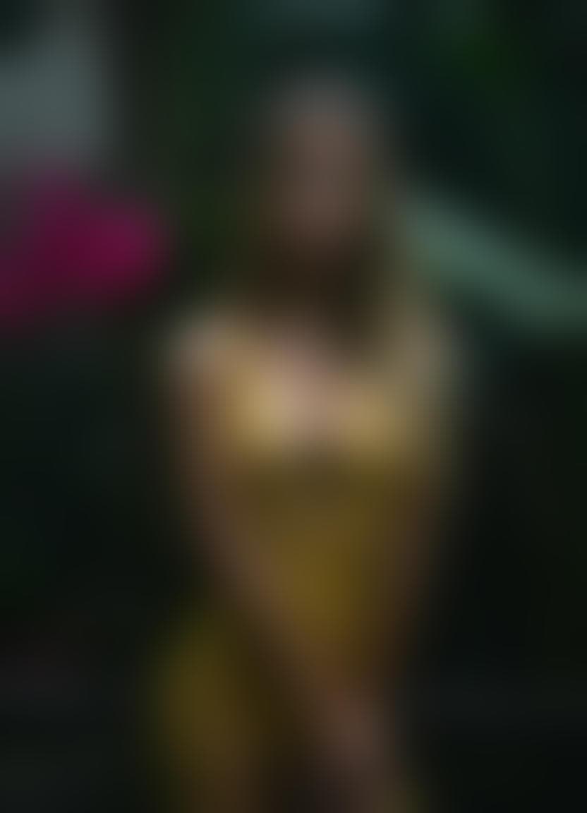 AI generated: The image is a portrait of a  woman posing in a tropical setting. She is wearing a yellow fishnet dr...