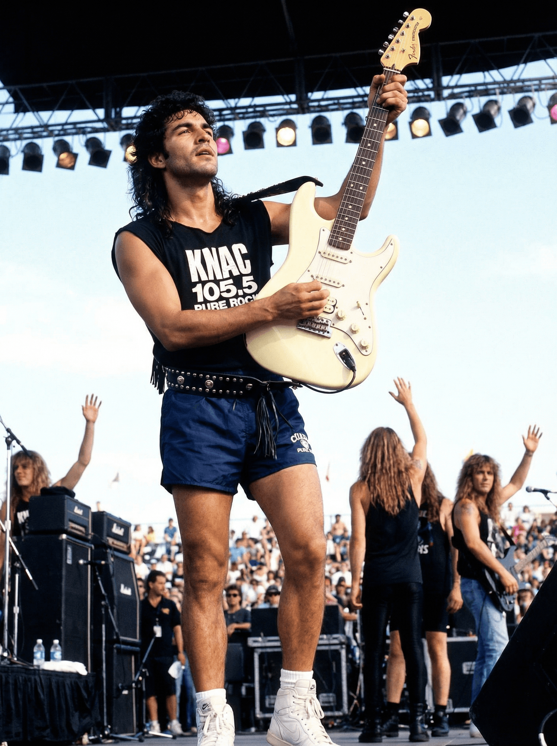 AI generated: An upshot of a Guitar player as he stands triumphant on the edge of the stage and holds his guitar b...