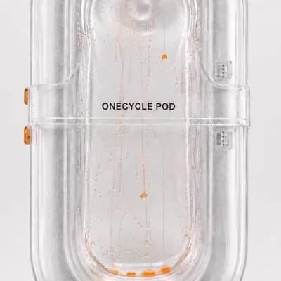 AI generated video: Animate only the tiny liquid orange droplets inside the transparent ONECYCLE POD. Keep the pod, labe...
