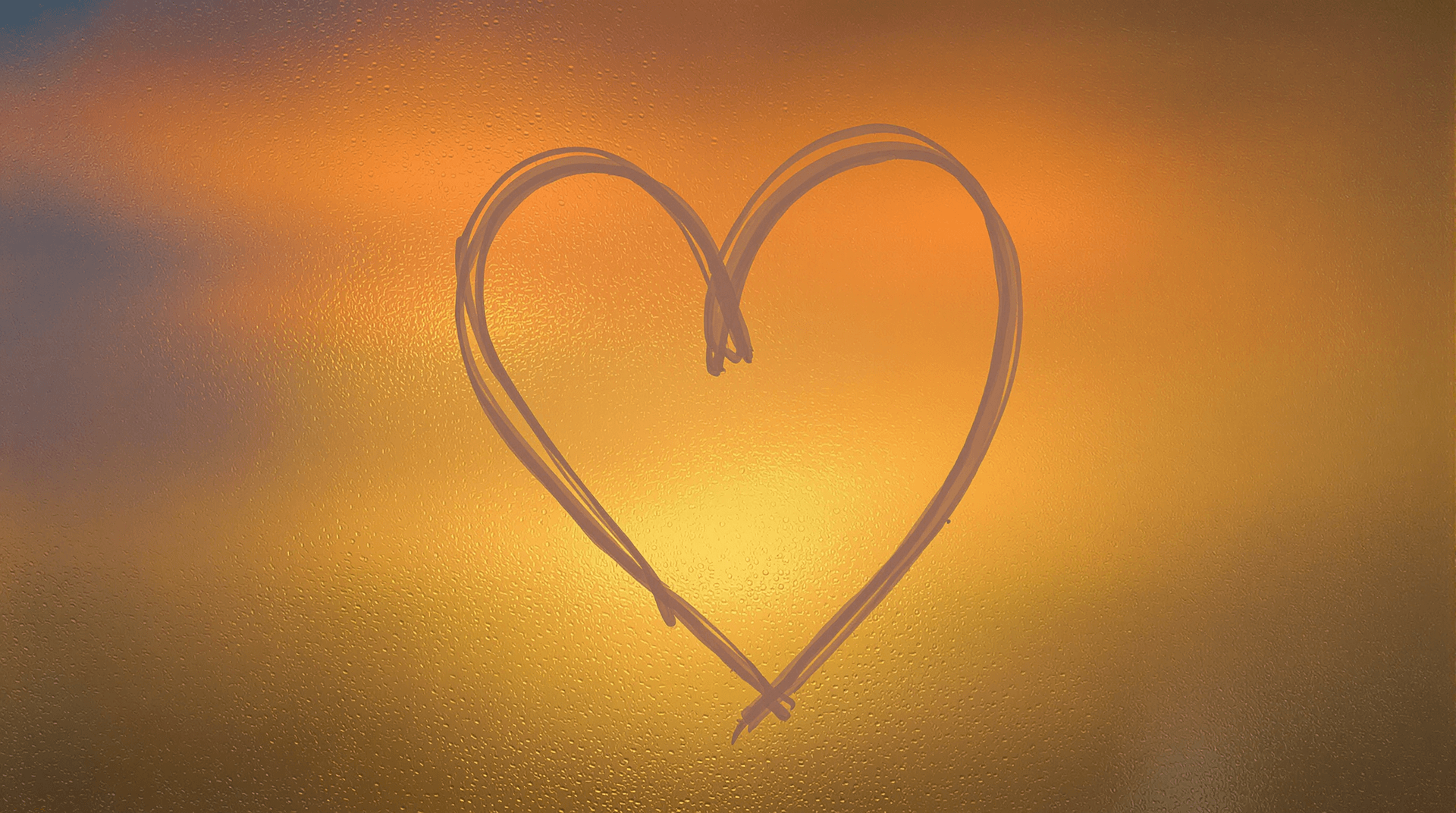 AI generated: A photograph of a heart shape drawn on a foggy glass window, with a gradient of warm colors in the b...