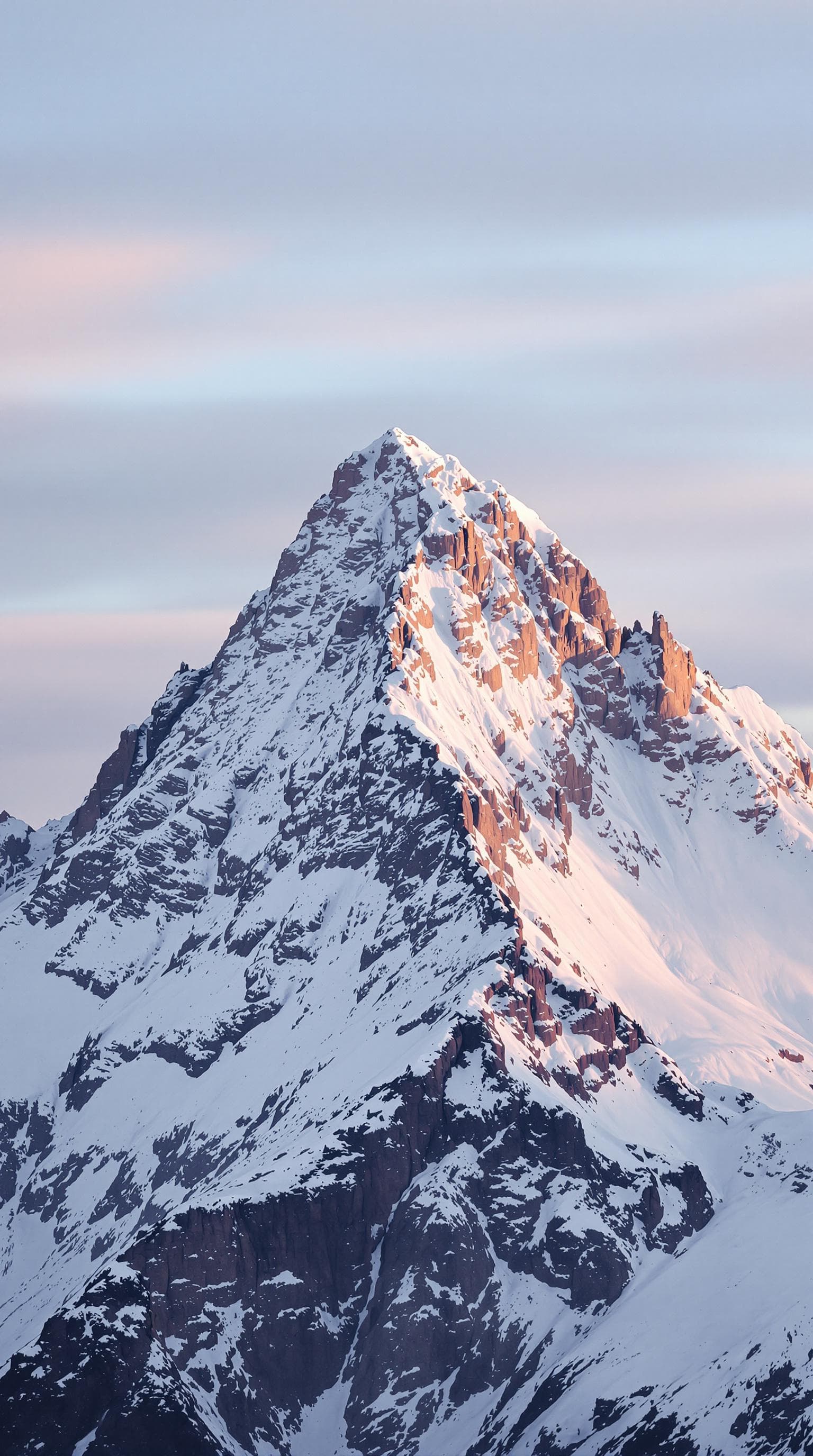 AI generated: A majestic snow-covered mountain peak at sunrise, with soft golden light illuminating the snowy slop...
