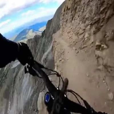 AI generated video: A realistic first-person video, filmed with a GoPro, of a professional athlete riding a bike down a ...