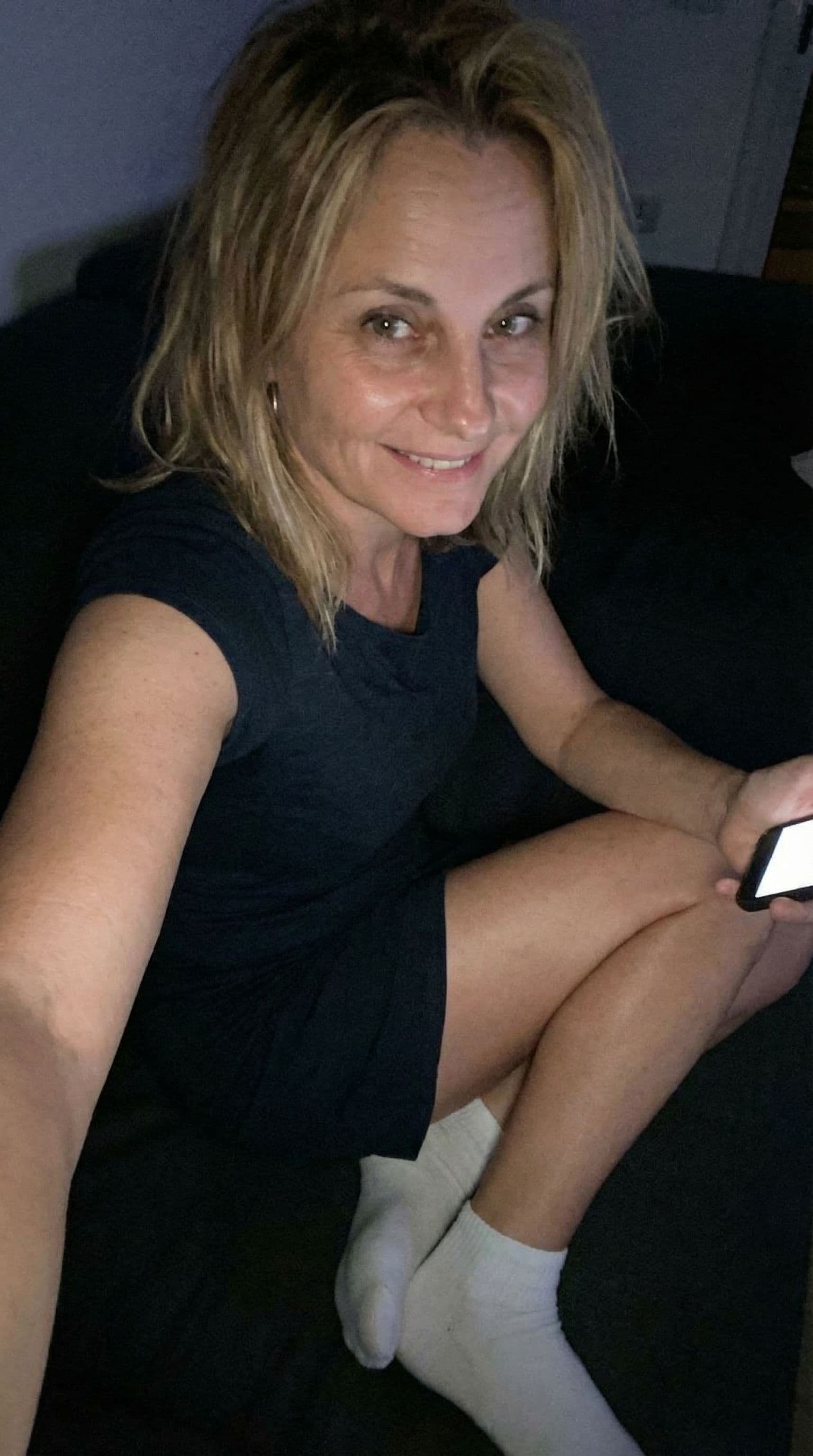 AI generated: Romantic selfie looking at me,a sloppy snapshot. Sitting on a couch at night teasing(no lights), wea...