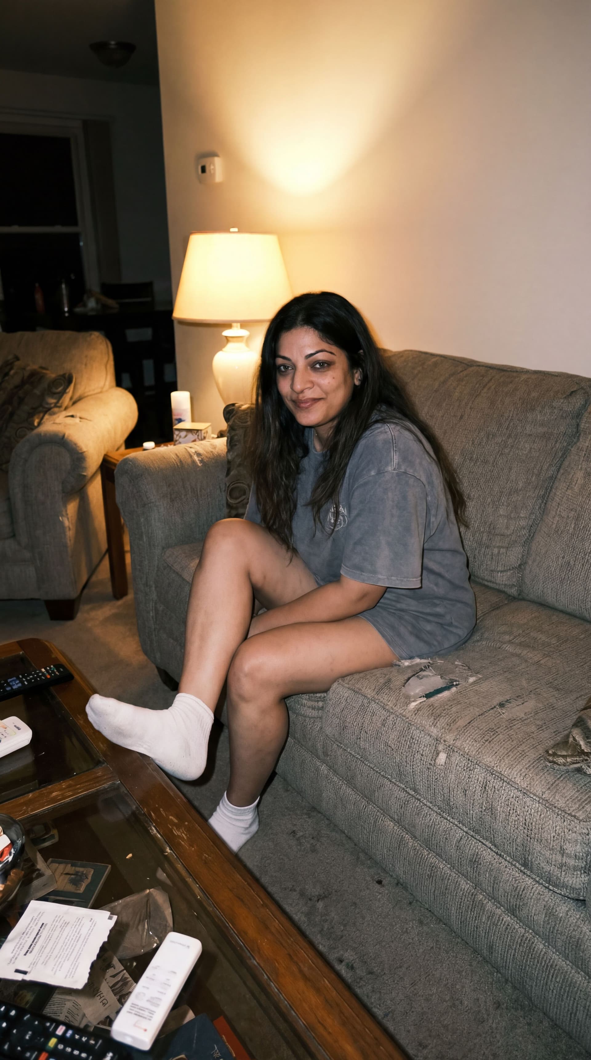 AI generated: looking at me,a sloppy snapshot. Sitting on a couch at night, home mini top and white socks