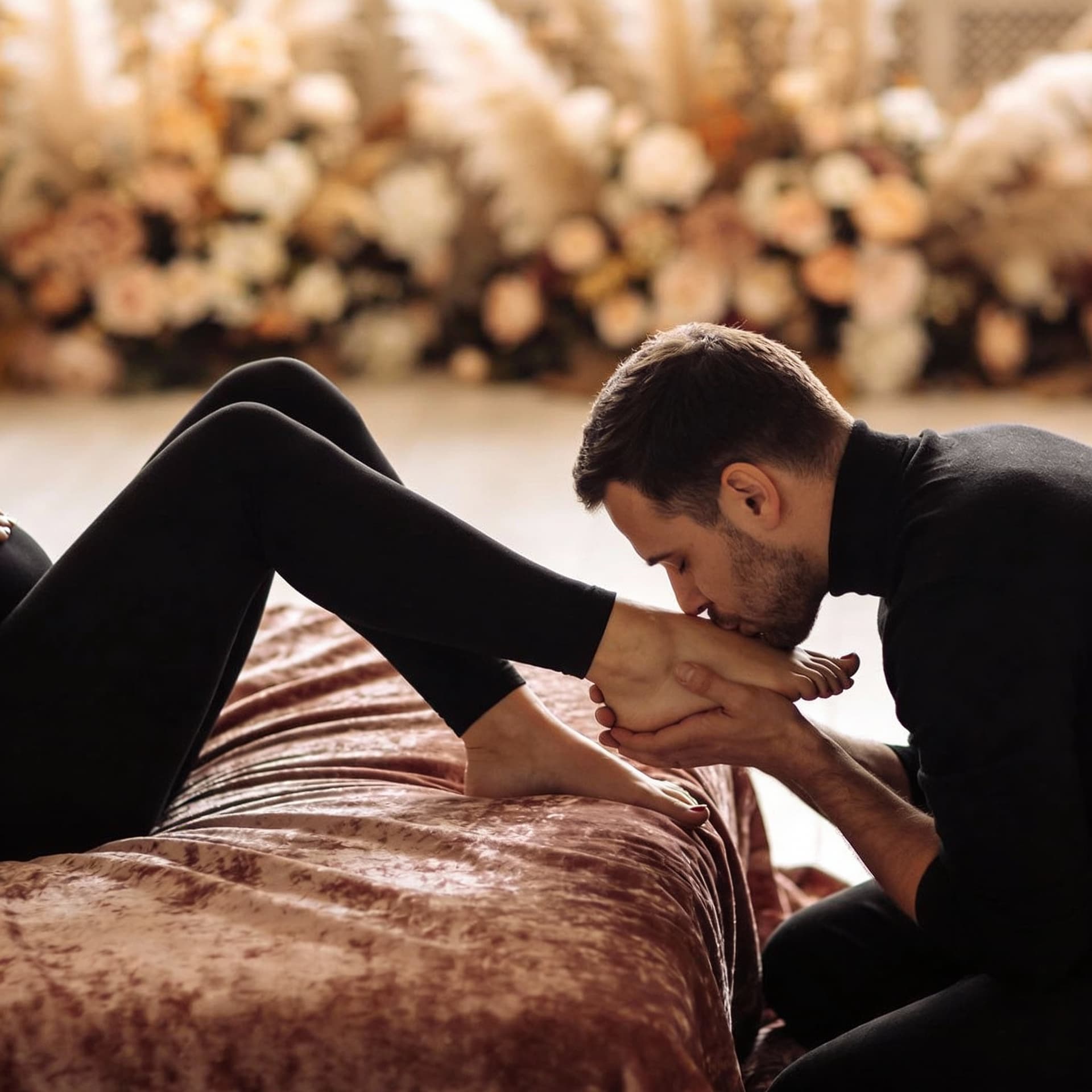 AI generated: A romantic, artistic scene of a couple — man gently kissing wife’s foot — in soft lighting, wife lay...