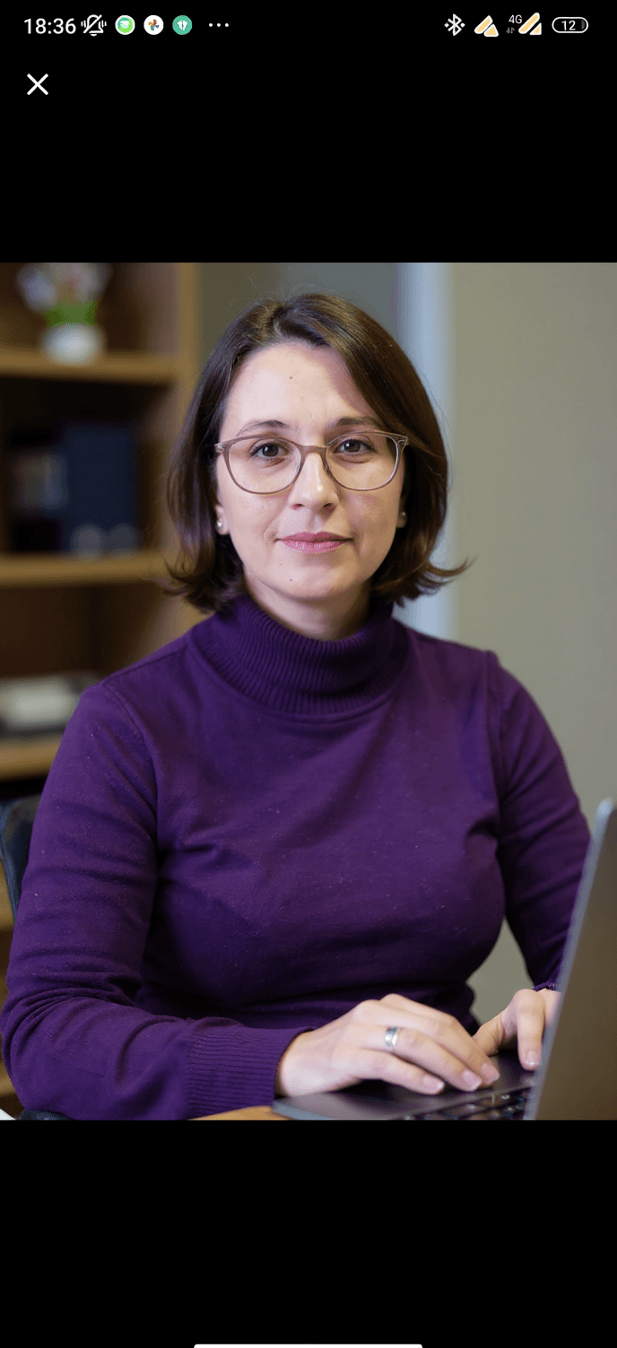 AI generated: Photo of a woman in an office, purple turtleneck, glasses, typing on a laptop. Studio soft lighting,...