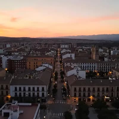 AI generated video: 6 segundos de vista aérea panorámica de Valdemoro al atardecer, transición suave hacia la fachada de...