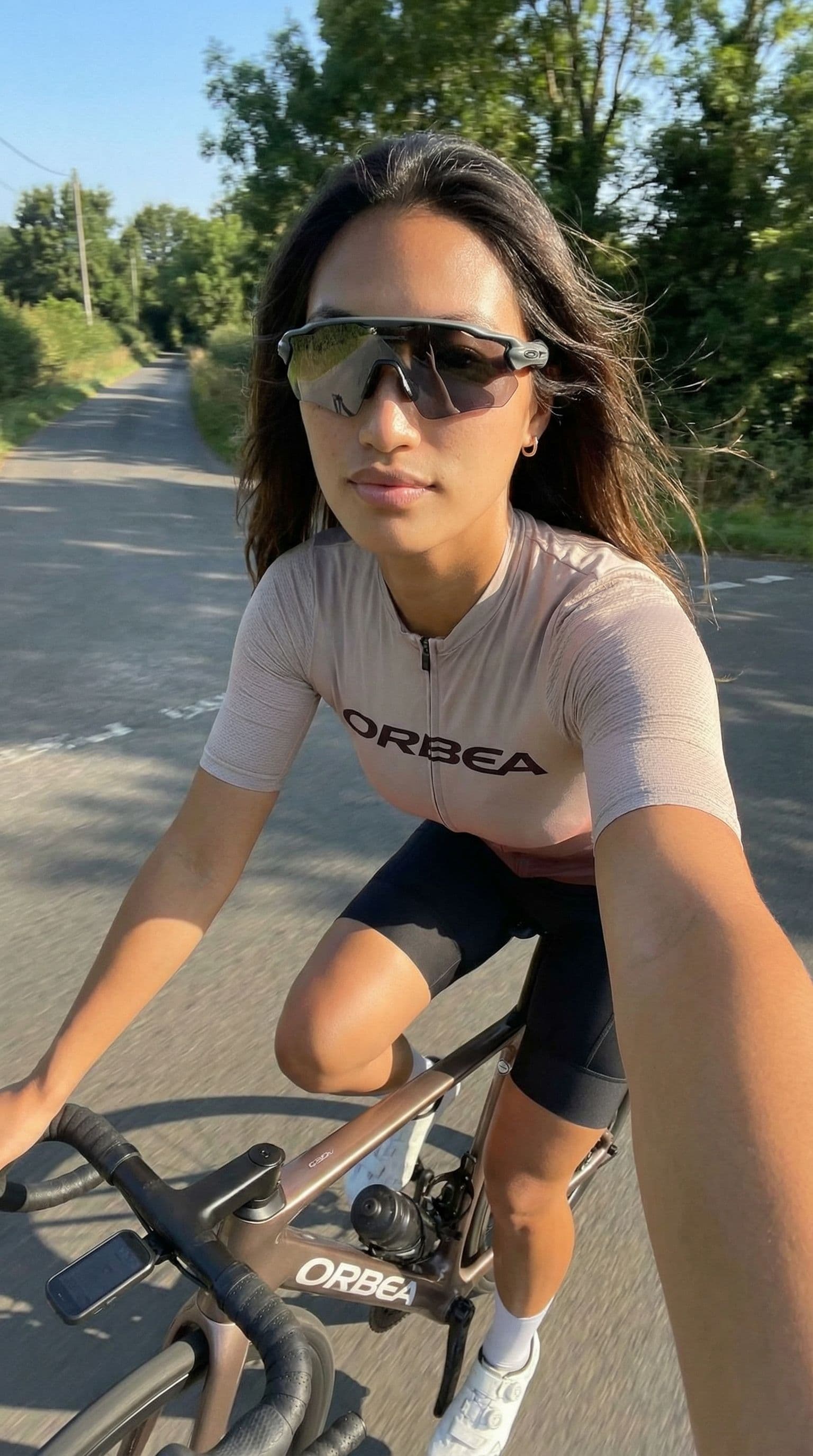 AI generated: A realistic iPhone-style selfie taken on a quiet road in daylight. The woman from the reference imag...
