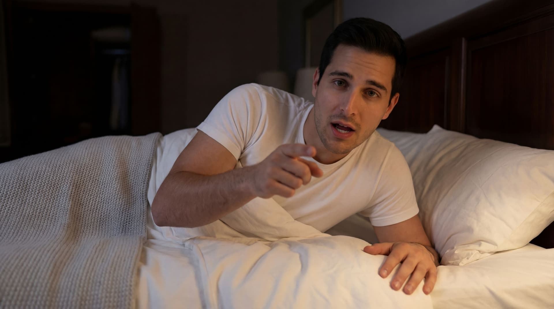 AI generated: The model is leaned over the bed on one hand, while pointing front with his finger with the other ha...