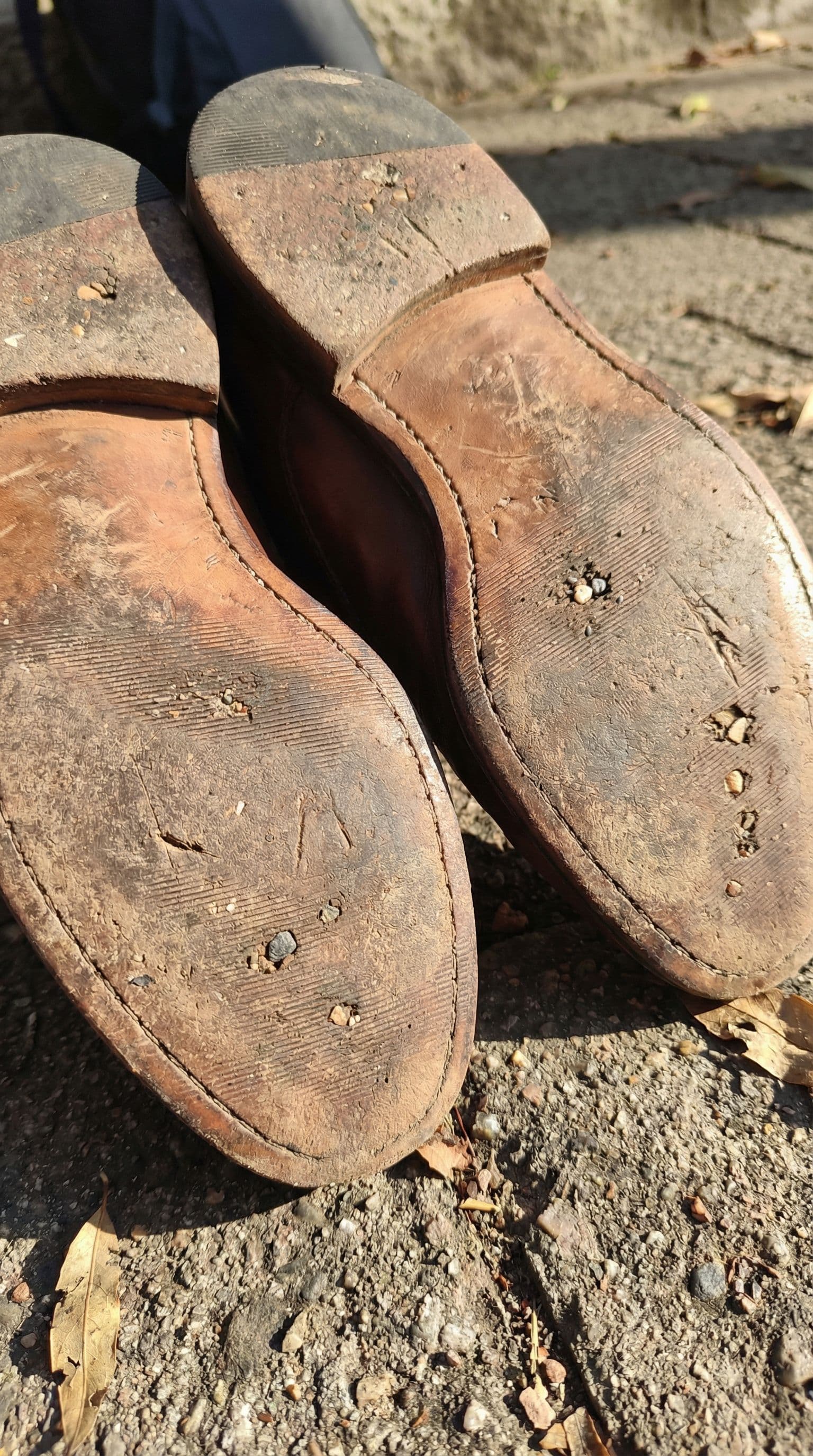 AI generated: A close-up shot focusing on the bouth girls soles of worn-in brown leather shoes, showcasing the tre...