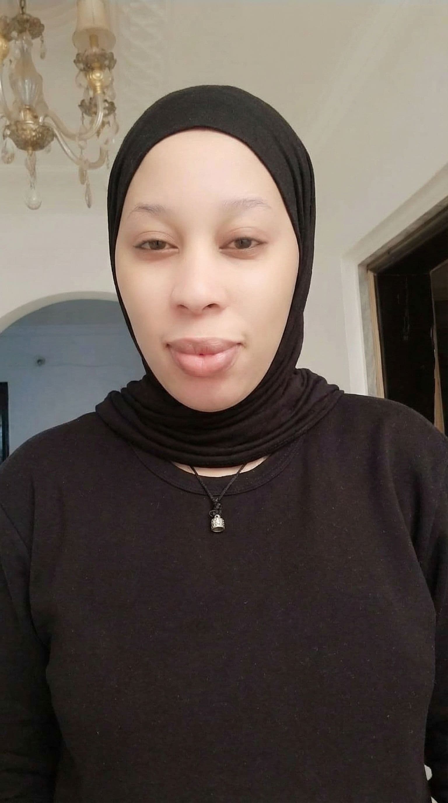 AI generated: woman on this photo take out the hair, wear hijab, maintain the authenticity of his face and pose.