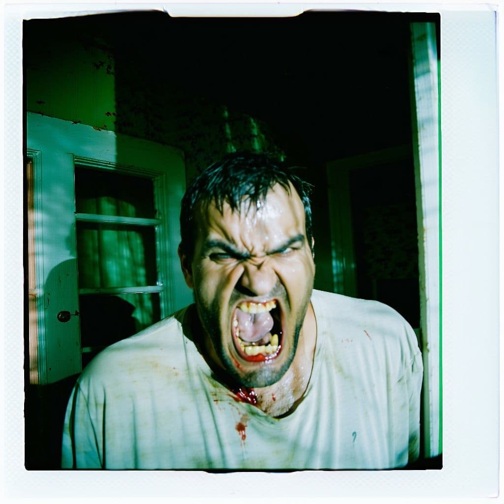 AI generated: grainy 80's photograph quality polaroid of the angriest and creepiest man caught in an abandoned hou...