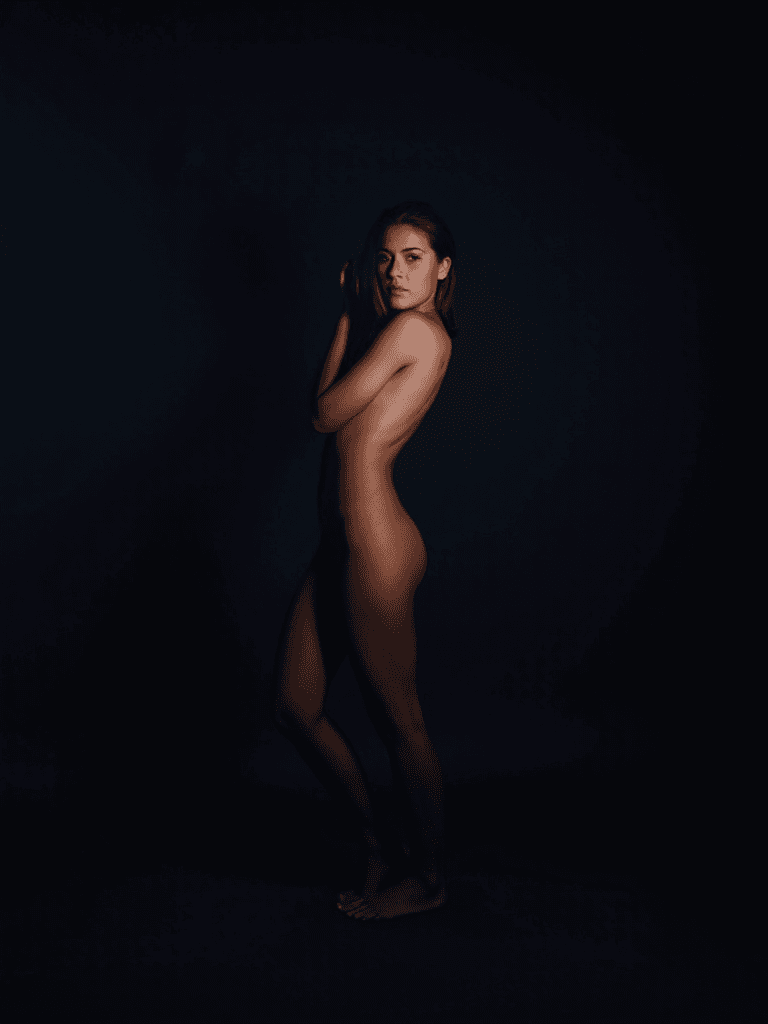 AI generated: A dark, intimate fine art portrait of a woman standing confidently against a deep, moody background....
