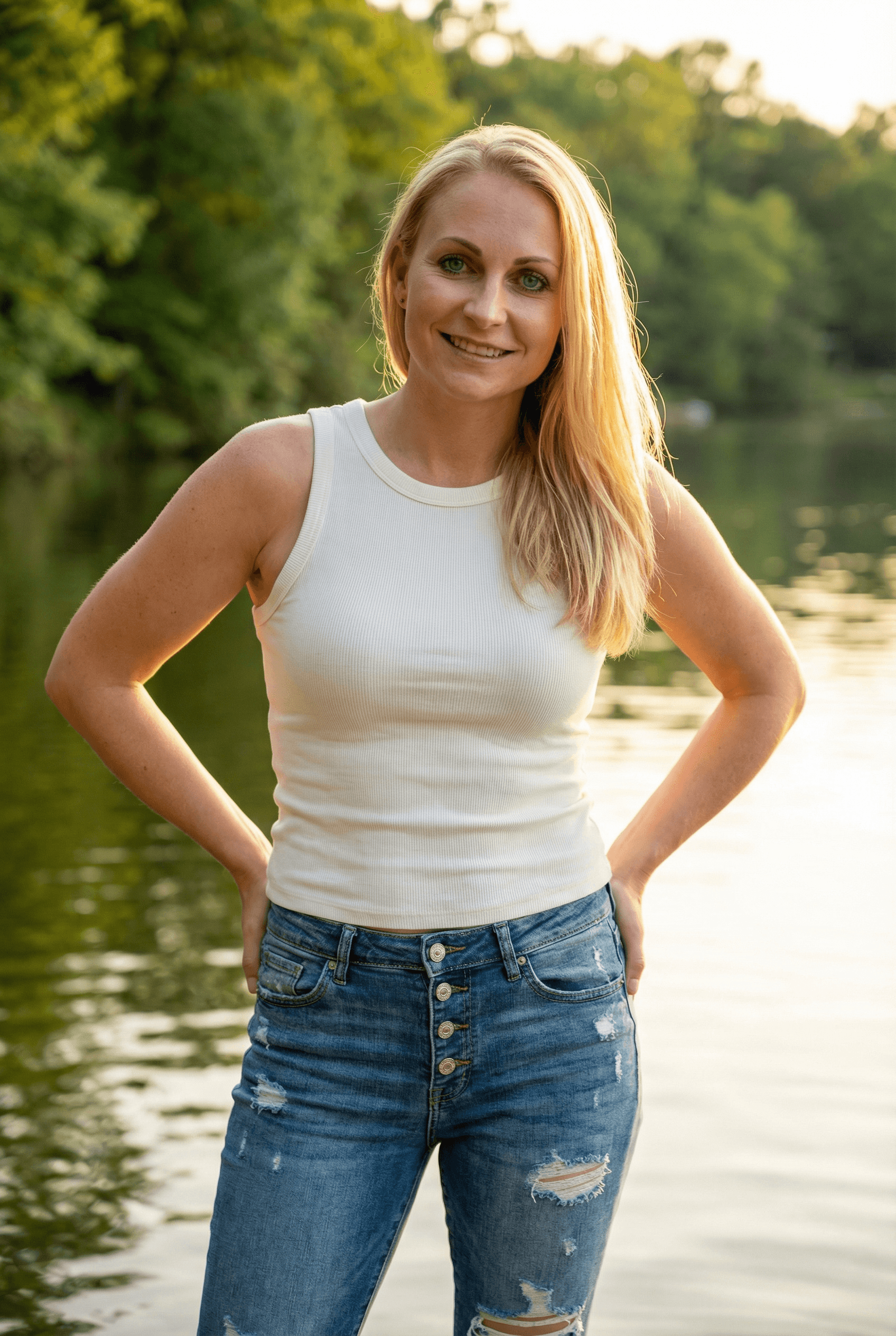 AI generated: A fit adult woman stands in a sunlit outdoor setting, facing the camera, her hands resting casually ...