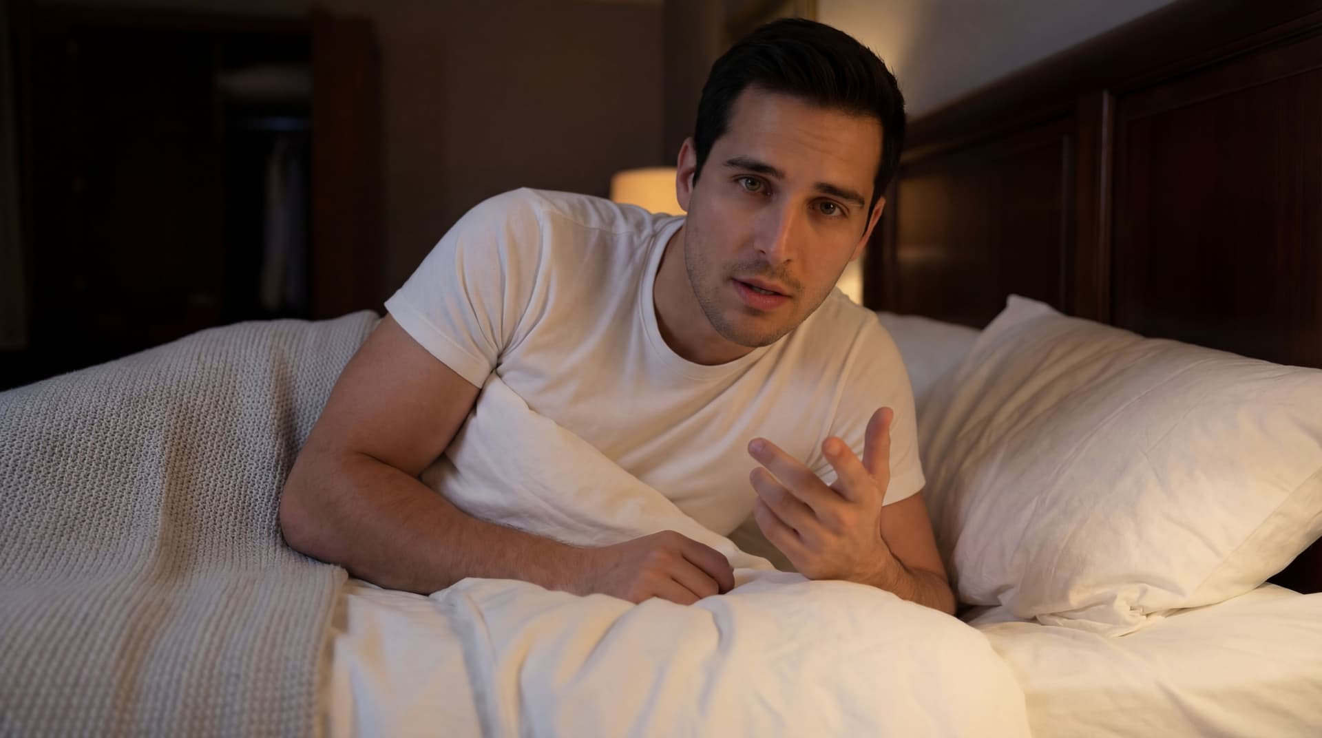 AI generated: The model is leaned over the bed on one hand, while expressing conversation with the other hand. His...