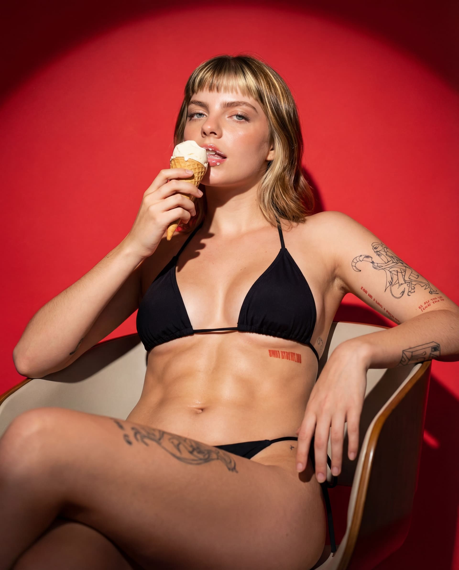 AI generated: 
Heroic up angle full body portrait, A sensual pose, Sitting in a chair, eating ice cream with my mo...