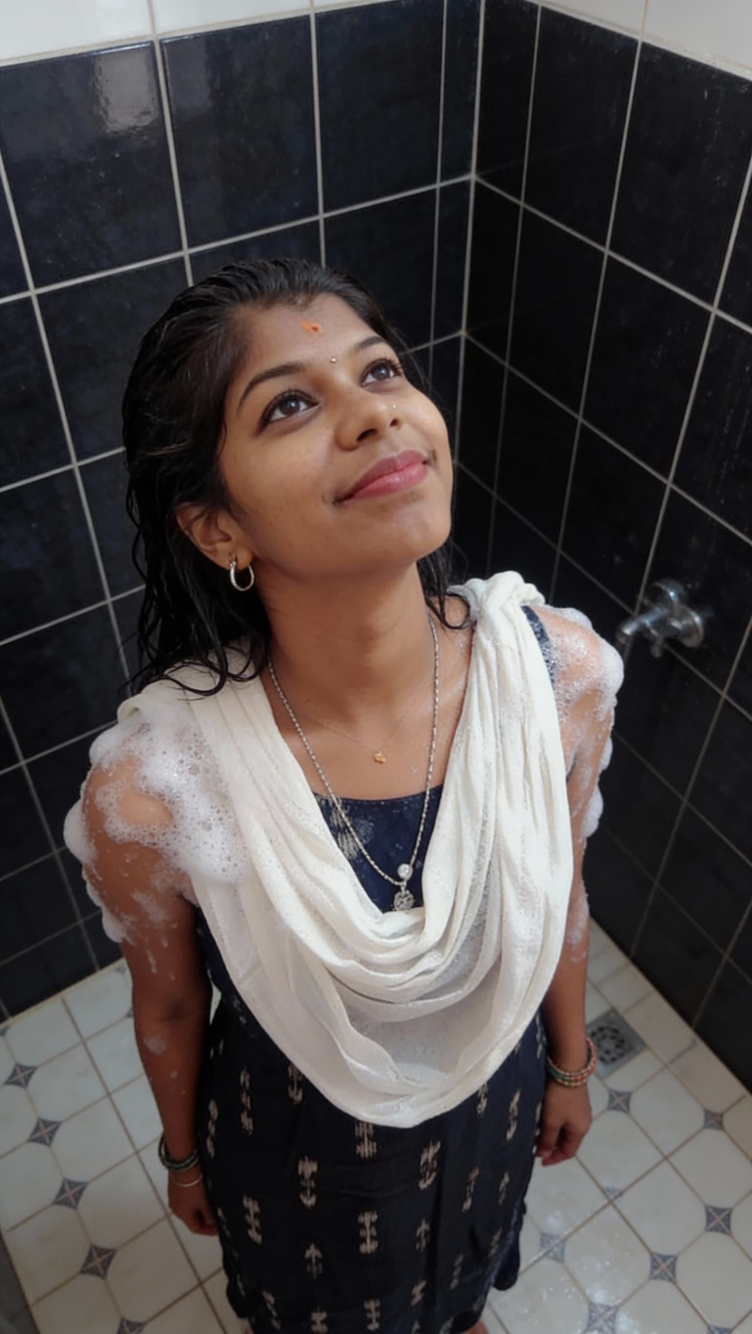 AI generated: The image shows an adult woman in a tiled shower area. She is wet and covered with soap suds across ...