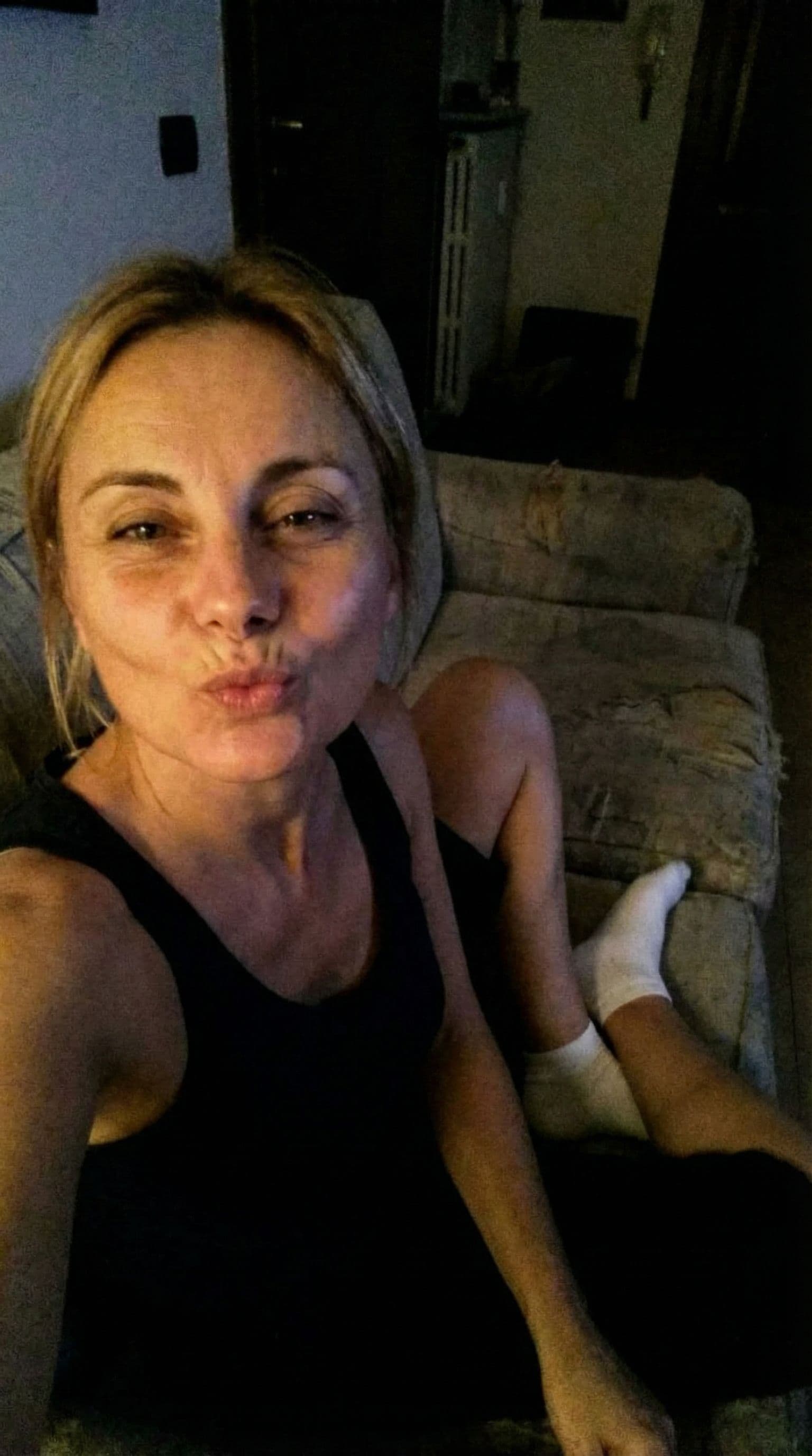 AI generated: Romantic selfie blowing a kiss at me,a sloppy snapshot. Sitting on a couch at night teasing(no light...