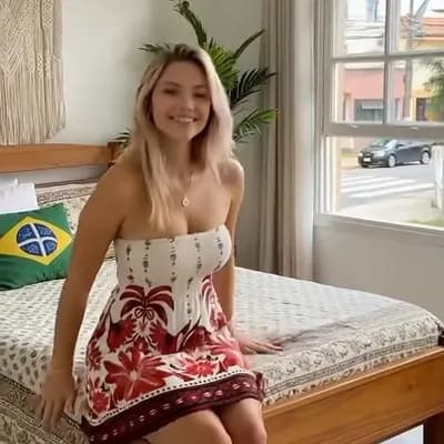 AI generated video: Medium shot, eye level. A young blonde woman, dressed in a white strapless mini-dress with a red flo...