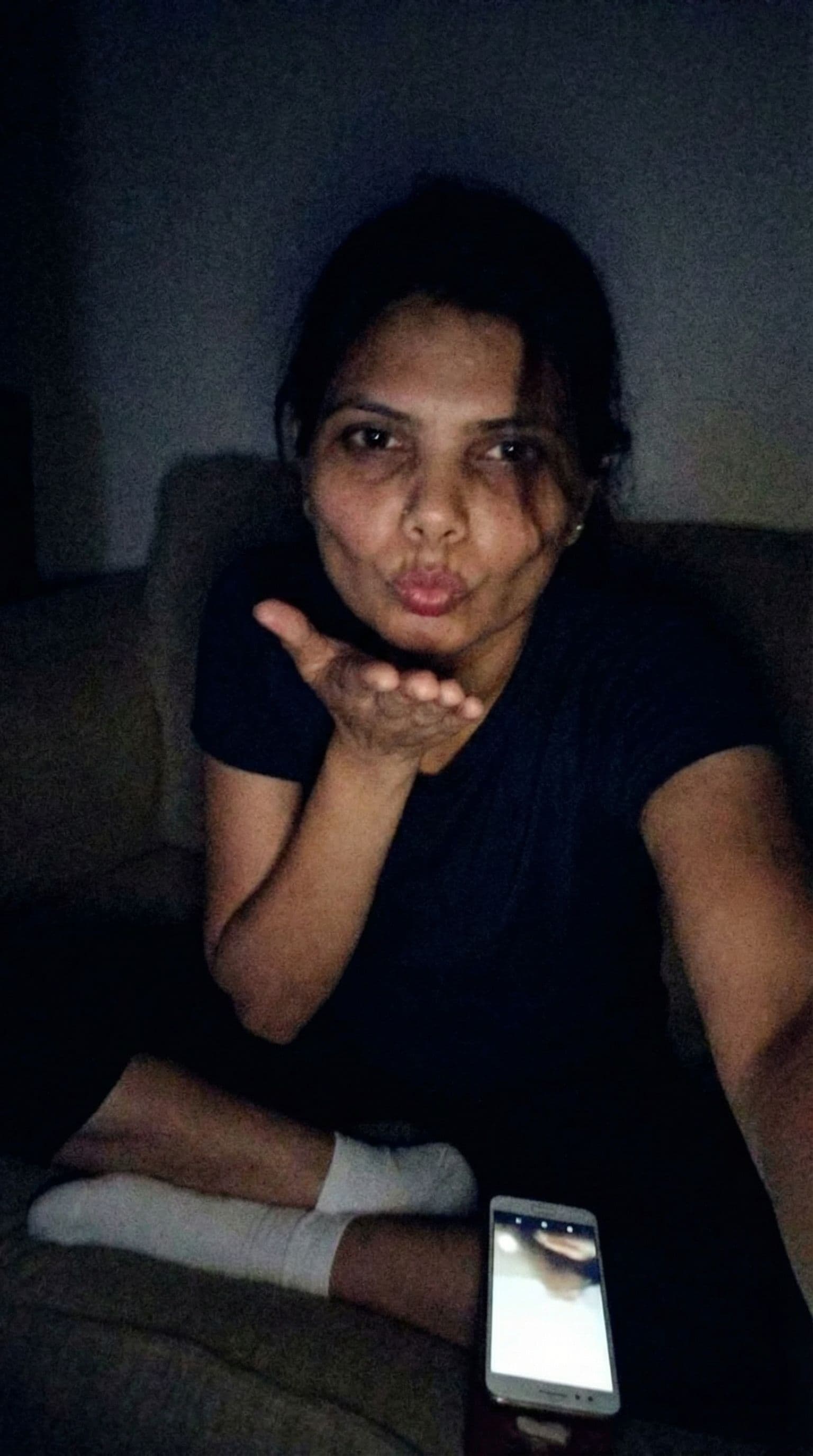 AI generated: Romantic selfie blowing a kiss at me,a sloppy snapshot. Sitting on a couch at night teasing(no light...