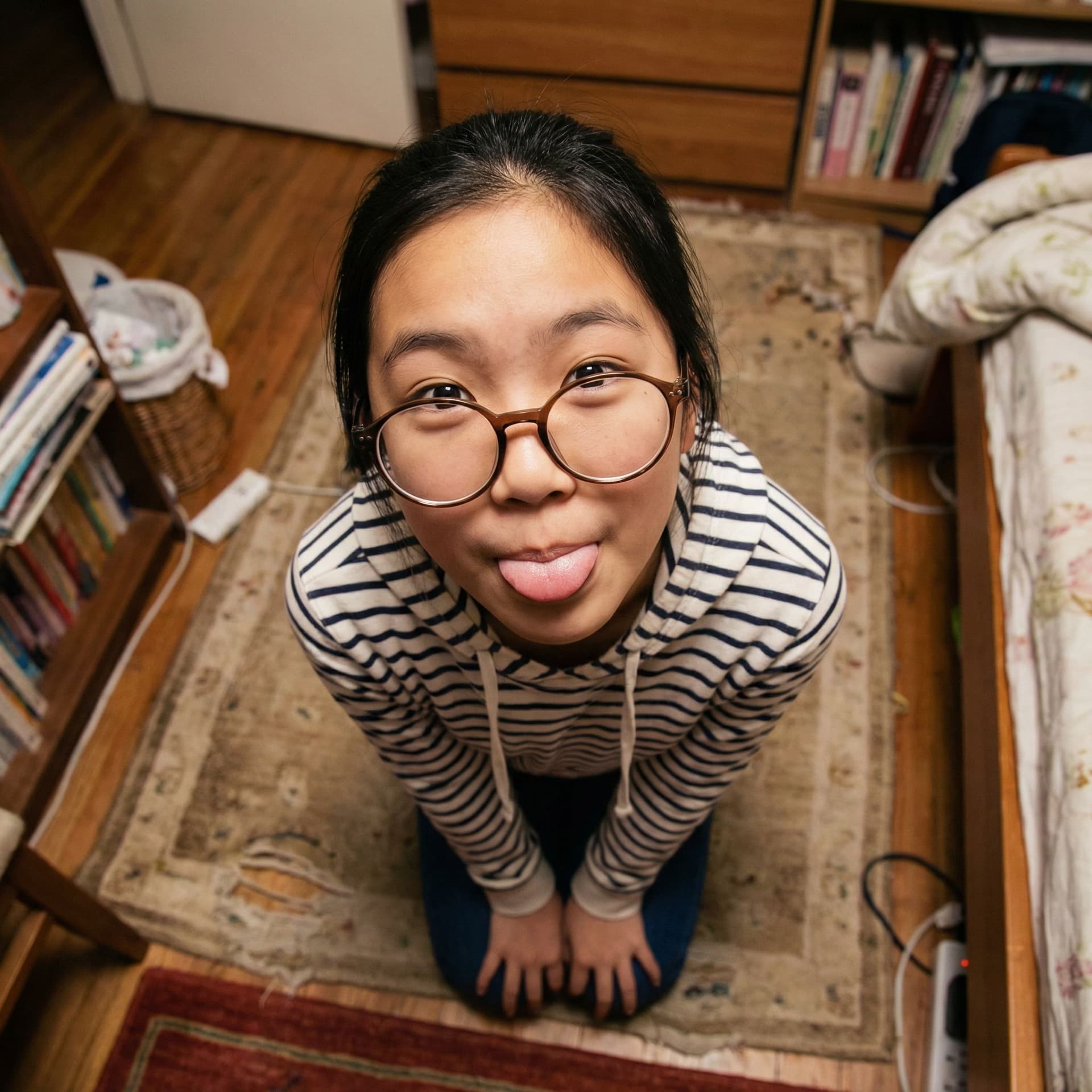 AI generated: Asian girl, 14 years old, large glasses on the tip of her nose, on her knees, looks up at the camera...