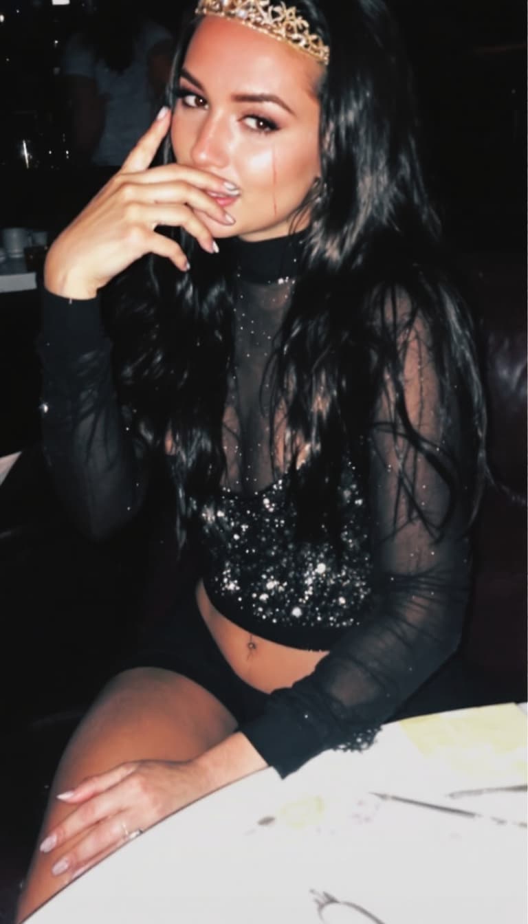 AI generated: casual photo in bar party The image shows a person with long dark hair wearing a black outfit with a...
