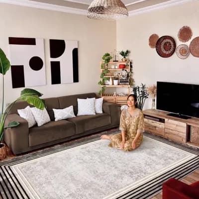 AI generated video: A cozy and modern living room with warm lighting and natural decor. A woman in a patterned dress is ...