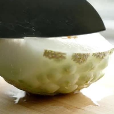 AI generated video: Close-up shot of an ultra-sharp knife slowly slicing through a crystal melon (also known as white ho...