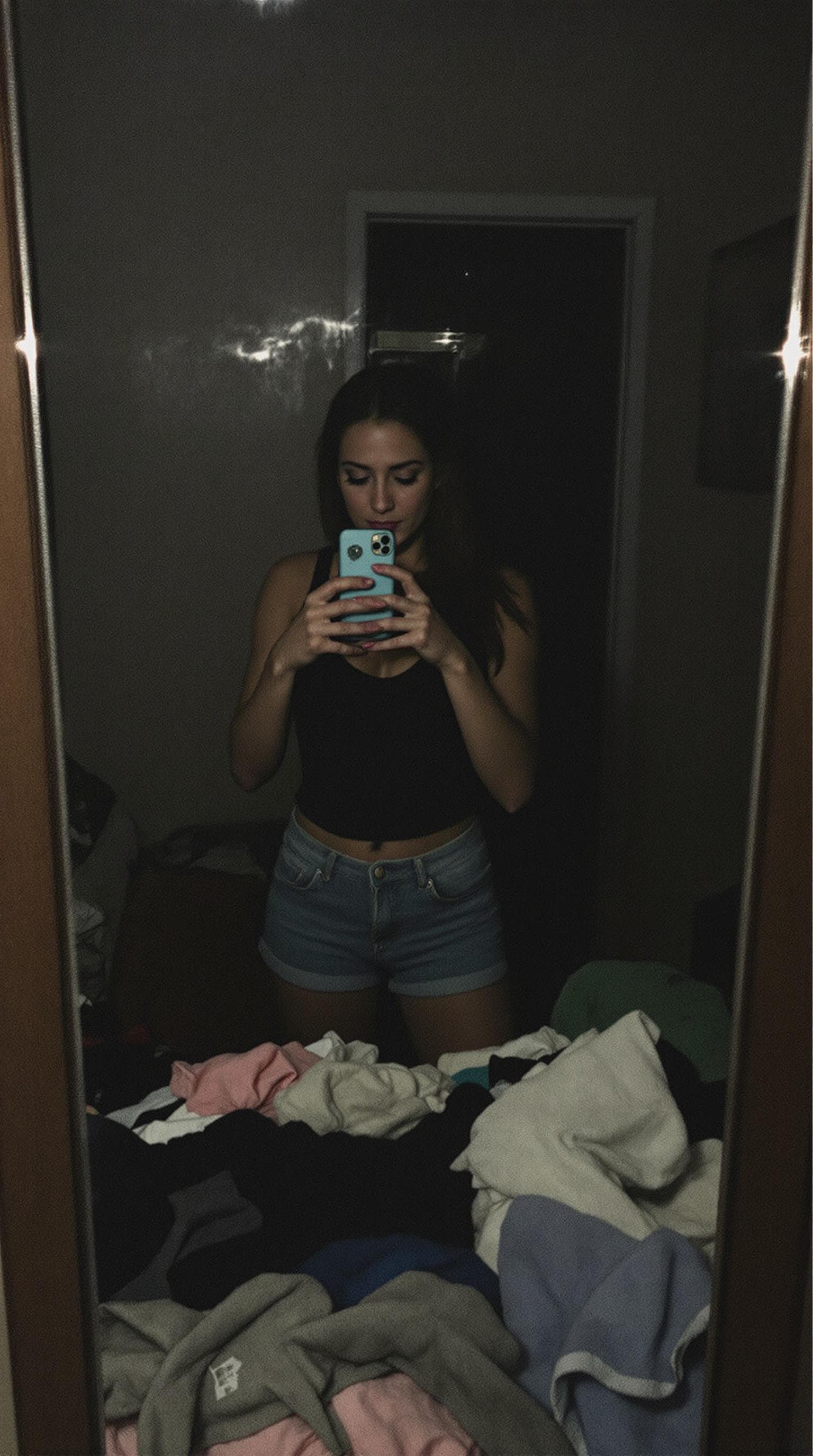 AI generated: A woman stands in front of a mirror, capturing a selfie. The image quality is grainy, with a slight ...
