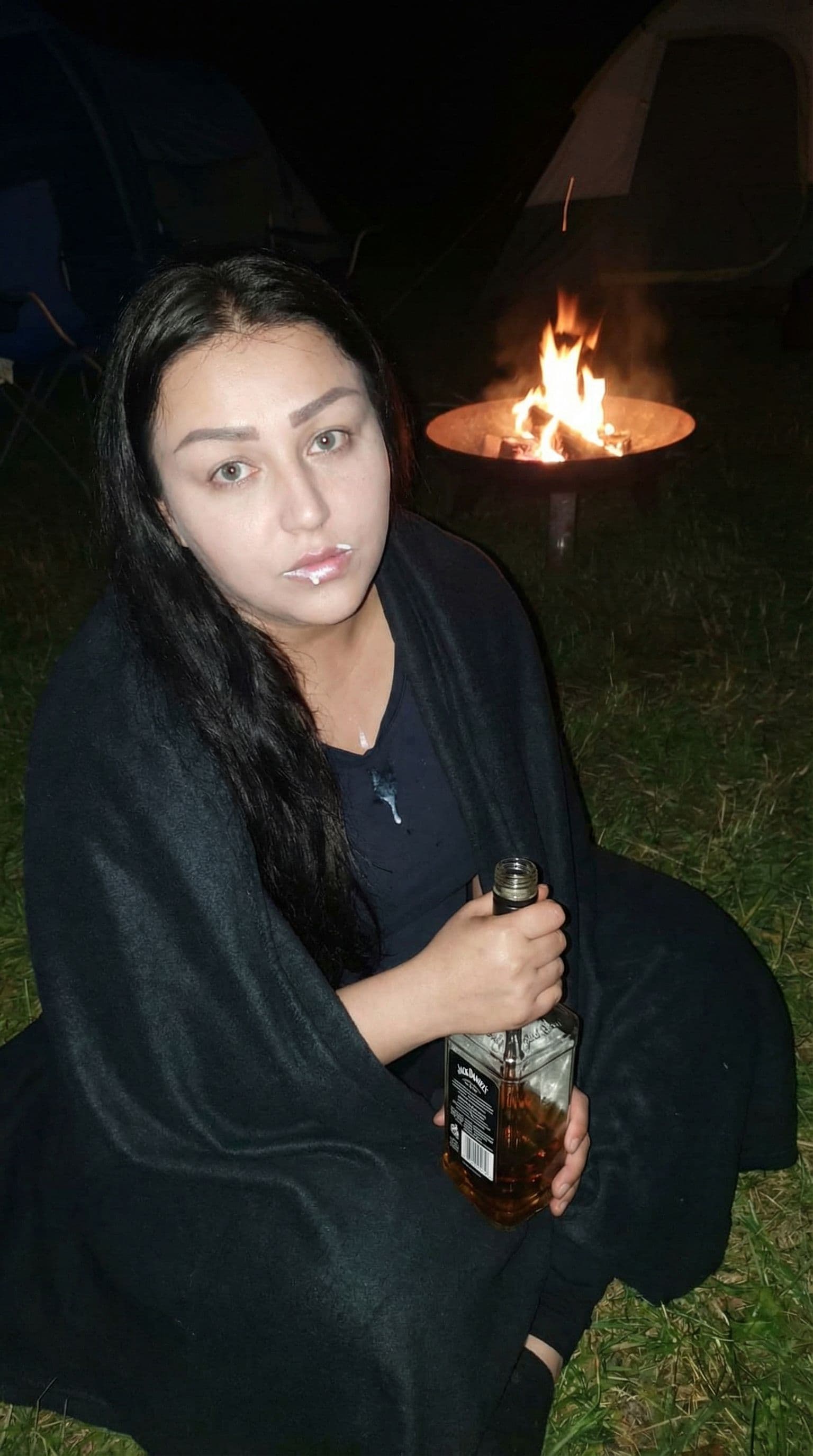 AI generated: 35 year old beauty in a camp by night, long dark black hair, around a fire, campsite, firepit, campf...